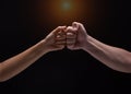 Close up of human hands making a fist bump on black background. a fist pump together after good deal Royalty Free Stock Photo