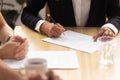 Close up human hands signing contract paper at business negotiations