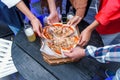 Close up human hands taking slices of hot tasty italian pizza from cardboard box at the party. Royalty Free Stock Photo