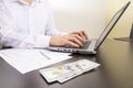 close-up of human hands typing on a computer keyboard. in the foreground are dollar bills Royalty Free Stock Photo