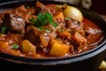 Close-up of Hungarian-style goulash with chunks of tender beef, onions, and potatoes, garnished with a sprig of thyme