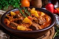 Close-up of Hungarian-style goulash with chunks of tender beef, onions, and potatoes, garnished with a sprig of thyme