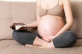 Close up of hungry pregnant woman is eating a piece of tasty cake relaxing on the sofa at home. Sweet cravings during pregnancy