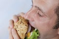Close-up. A hungry young man eats a big hamburger sandwich with beef, tomatoes, onions, sauce, cheese, lettuce and a sesame bun Royalty Free Stock Photo