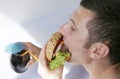 Close-up. A hungry young man eats a big hamburger sandwich with beef, tomatoes, onions, sauce, cheese, lettuce and a sesame bun Royalty Free Stock Photo