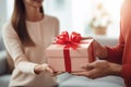 Close-up, husband surprises wife with gift, Valentine& x27;s Day, living room sofa, focus on present.