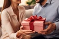 Close-up, husband surprises wife with gift, Valentine& x27;s Day, living room sofa, focus on present.