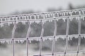 Close up of ice covers wire fence with ice icicles Royalty Free Stock Photo