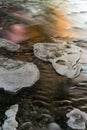 Close-up of ice formations on a flowing river with colorful reflections at sunset. Royalty Free Stock Photo