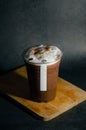 Close up of iced cocoa in plastic glass with white sticker tag on wooden plate