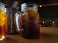 Iced tea in a mason jar with ice cubes in it. Put it on the cafÃÂ© table next to the spoon and fork stainless mug. Royalty Free Stock Photo