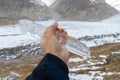 Close up of Icicle held in front of glacier and mountain landscape at the aletsch glacier. Showing movement against