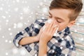 Close up of ill boy lying in bed and blowing nose Royalty Free Stock Photo