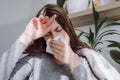 Close-up ill young girl blowing running nose got fever caught cold sneezing in tissue sitting on sofa, sick allergic female Royalty Free Stock Photo
