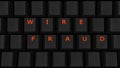 Close Up of Illuminated Glowing Keys on a Black Keyboard Spelling Wire Fraud