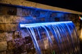 A close-up of an illuminated home waterfall at night