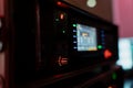 Close-up of illuminated stage control equipment showing glowing knobs, signal indicators and blurry digital screen Royalty Free Stock Photo