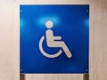 White Handicap Parking Sign on Blue Plate Against Wall Royalty Free Stock Photo