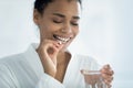 Closeup image african woman taking pill holding glass of water