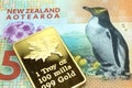 A New Zealand five dollar bill with a gold coin close up