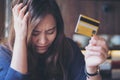 Asian woman close her eyes while holding credit card with feeling stressed and broke