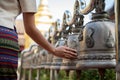 Close-up image of an Asian woman in a traditional Thai dress is ringing temple bells in a temple