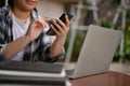 Close-up image of an Asian woman using her smartphone while remote working at outdoor cafe Royalty Free Stock Photo