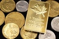 A close up image of an assortment of Israeli coins with a Canadian one ounce gold on a black background