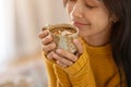 A beautiful Asian woman in a sweater eyes closed, holding a cup of hot cocoa, enjoying it at home Royalty Free Stock Photo