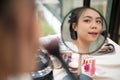 Close-up image of a beautiful Asian woman looking at the mirror while applying makeup in her room Royalty Free Stock Photo