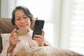 Beautiful 60s aged-asian woman paying her bills with mobile banking application Royalty Free Stock Photo