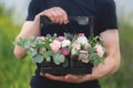 Flower arrangement in a wooden box with spray pink roses, succulent, eustoma, white hypericum, eucaliptus in man& x27;s hands Royalty Free Stock Photo