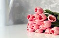 Close up image of beautiful pink tulip bouquet on white table with vase in the background in bright room Royalty Free Stock Photo
