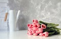 Close up image of beautiful pink tulip bouquet on white table with vase in the background in bright room Royalty Free Stock Photo