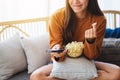 A beautiful young woman eating pop corn and searching channel with remote control to watch tv while sitting on Royalty Free Stock Photo