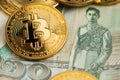 Close up image of Bitcoin cryptocurrency coins and Thailand Baht currency banknotes.