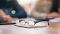 A black eyeglasses on notebook with blur businessman in office