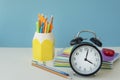 close up image of black round clock and different school supplies on light background. Royalty Free Stock Photo