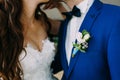 Close-up image of a Boutonniere on the groom`s jacket. Blurred bride and groom are kissing. Artwork Royalty Free Stock Photo