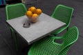 Close up image of a bowl of ripe oranges on a square table surrounded by three, green plastic chairs on a Jerusalem sidewalk Royalty Free Stock Photo
