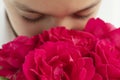 Close up image of boy`s face hiding into big bouquet of red roses Royalty Free Stock Photo