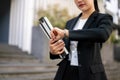 A busy Asian businesswoman is checking time on her wristwatch while walking in the city street Royalty Free Stock Photo