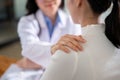 Close-up image of a caring female doctor or psychiatrist is touching a patient\'s shoulder