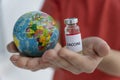 Close up image of child`s hands not in focus holding toy globe in one hand and ampoule with vaccine on another. Royalty Free Stock Photo