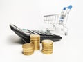 Close up image coins stacked with blurry calculator and trolley. Royalty Free Stock Photo