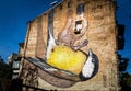 Close-up image of a colorful bird painted on the side of an exterior brick wall