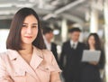 Confident beautiful Asian business woman in beige color  suit standing in front of her team, smiling and looking at camera Royalty Free Stock Photo