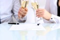 Close-up image of a contract . two colleagues celebrate signing a contract with champagne