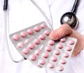 Close-up image of a doctor holding pink pills