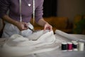 Close-up image of a dressmaker using scissors to cut the fabric, making fabric pattern